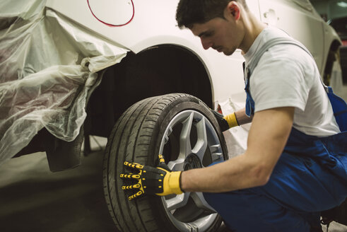 Mechaniker wechselt Autoreifen in seiner Werkstatt - RAEF02025