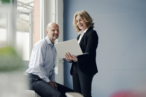 Businessman and businesswoman working together on laptop - KNSF03801