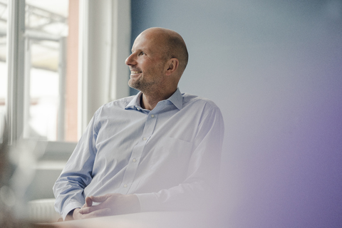 Smiling mature businessman looking out of window stock photo