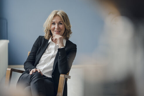 Portrait of smiling senior businesswoman sitting in chair - KNSF03809