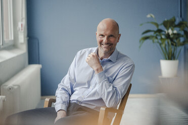 Portrait of smiling mature businessman sitting in chair - KNSF03810