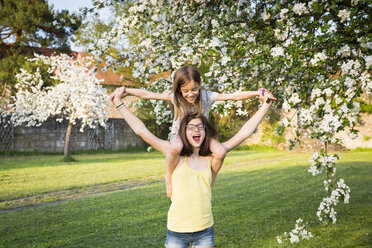 Girl carrying little sister on her shoulders in the garden - LVF06931
