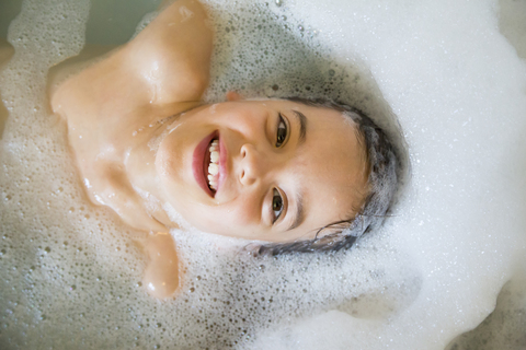 Porträt eines glücklichen kleinen Mädchens beim Baden in einer Wanne, lizenzfreies Stockfoto