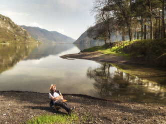 Italy, Lombardy, senior man relaxing at Lake Idro - LAF02015