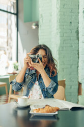 Lachende Frau, die in einem Café sitzt und mit der Kamera fotografiert - JPF00313