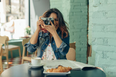 Lachende Frau, die in einem Café sitzt und mit der Kamera fotografiert - JPF00315