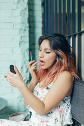 Portrait of young woman applying lip gloss - JPF00320