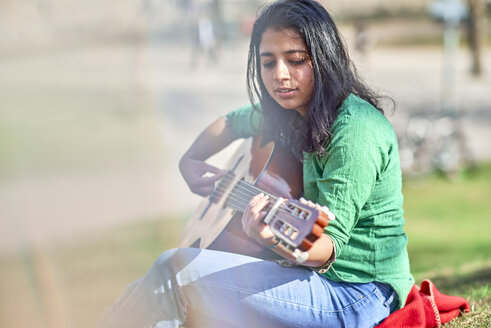 Junge Frau spielt Gitarre in einem Park - BEF00019