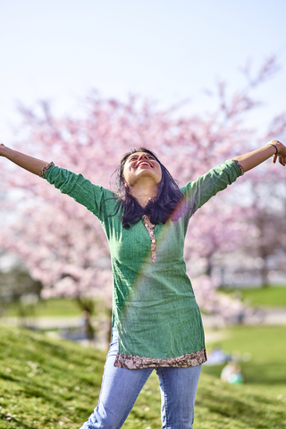 Happy young woman in a park at cherry blossom tree stock photo