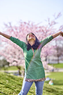 Glückliche junge Frau in einem Park an einem Kirschblütenbaum - BEF00024