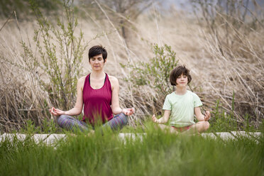 Mother and daughter doing yoga on boardwalk - JSMF00177