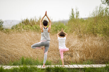 Rückansicht von Mutter und Tochter beim Yoga auf der Strandpromenade - JSMF00181