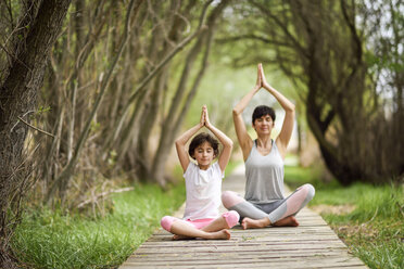 Mother and daughter doing yoga on boardwalk - JSMF00189