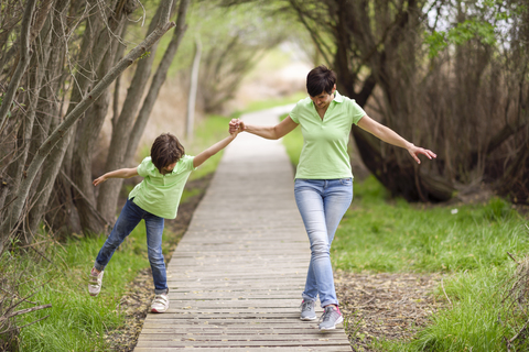 Mother and daughter walking hand in hand on boardwalk stock photo