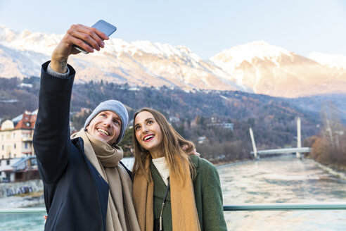 Österreich, Innsbruck, Porträt eines glücklichen jungen Paares, das im Winter ein Selfie mit seinem Smartphone macht - WPEF00225