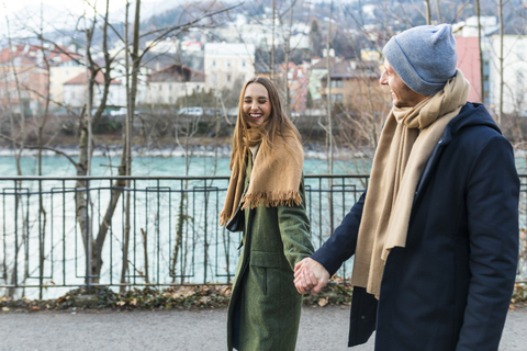 Österreich, Innsbruck, glückliches junges Paar, das im Winter Hand in Hand spazieren geht, lizenzfreies Stockfoto
