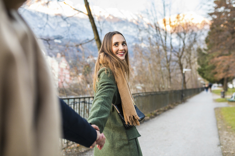 Austria, Innsbruck, portrait of happy young woman strolling hand in hand with her boyfriend at winter time stock photo