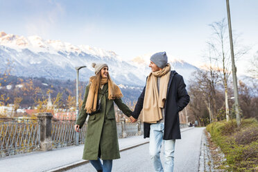 Österreich, Innsbruck, glückliches junges Paar, das im Winter Hand in Hand spazieren geht - WPEF00232