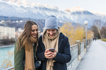 Österreich, Innsbruck, glückliches junges Paar schaut auf Handy - WPEF00233