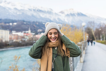 Austria, Innsbruck, portrait of young woman putting on her cap - WPEF00234