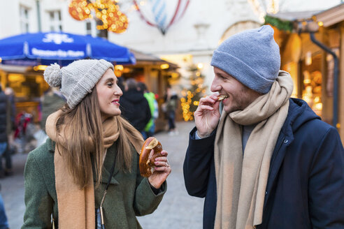 Junges Paar isst zusammen eine Brezel auf dem Weihnachtsmarkt - WPEF00237