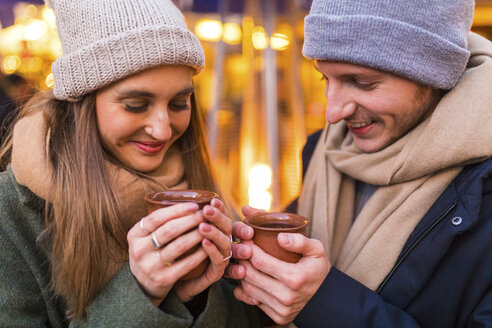 Happy young couple with cups of mulled wine at Christmas market - WPEF00241