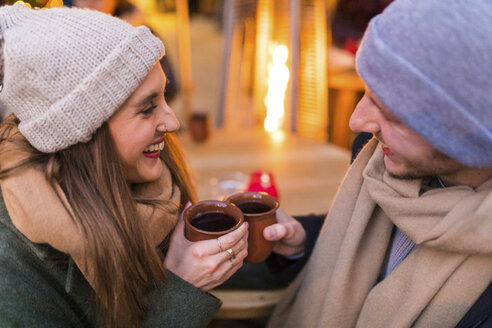 Glückliches junges Paar trinkt Glühwein auf dem Weihnachtsmarkt - WPEF00242