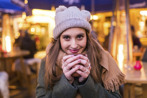 Porträt einer zufriedenen jungen Frau beim Glühweintrinken auf dem Weihnachtsmarkt - WPEF00243