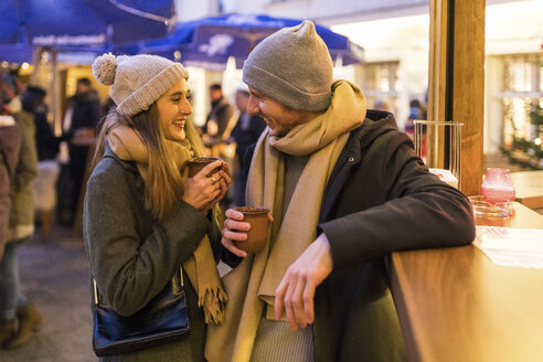 Glückliches junges Paar trinkt Glühwein auf dem Weihnachtsmarkt - WPEF00245