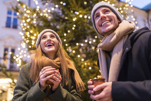 Laughing young couple drinking mulled wine at Christmas market - WPEF00246