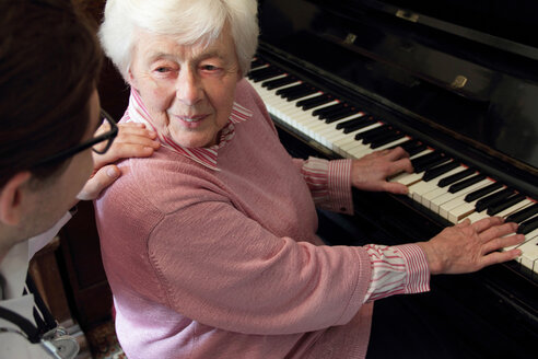 Doctor watching older woman play piano - CUF00730