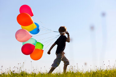 Junge mit bunten Luftballons im Gras - CUF00769