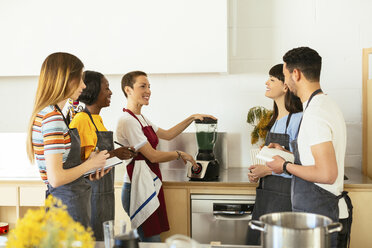 Freunde und Kursleiter in einem Kochworkshop bereiten einen Smoothie zu - EBSF02423