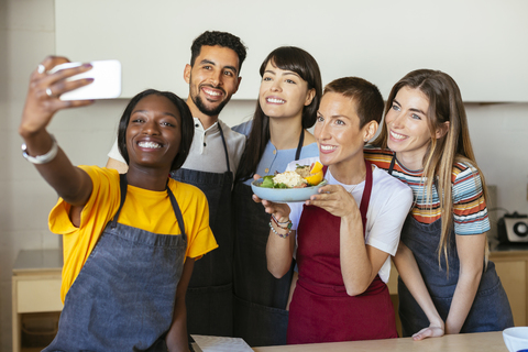 Freunde und Ausbilder in einem Kochworkshop machen ein Selfie, lizenzfreies Stockfoto