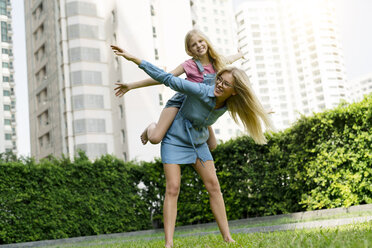 Happy mother and daughter having fun in urban city garden - SBOF01467