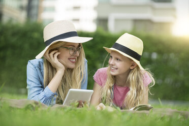 Glückliche Mutter und Tochter mit Buch und Smartphone im städtischen Stadtgarten - SBOF01475