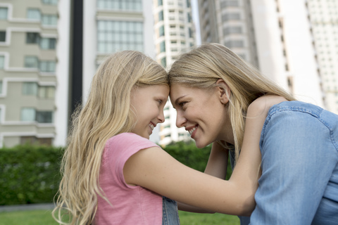 Happy mother and daughter smiling at each other urban city garden stock photo