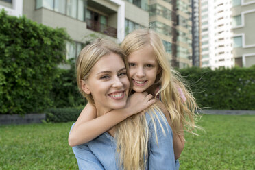 Glückliche Mutter und Tochter umarmen sich und lächeln im städtischen Garten - SBOF01483