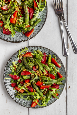 Salat von grünem Spargel, Rucola, Erdbeeren und Pinienkernen, lizenzfreies Stockfoto