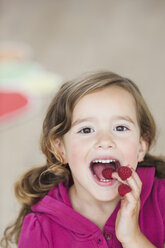 Young girl eating berries from fingers - CUF00809