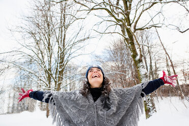 Woman in snowy woods embracing sky - CUF00853