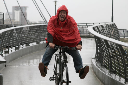 Mann im Regen auf dem Fahrrad hat Spaß - CUF00856