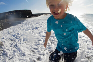 Boy playing in waves on beach - CUF00884