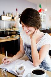 Lächelnde Frau beim Schreiben im Cafe - CUF00901