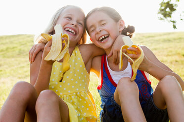 Lachende Mädchen essen Bananen im Freien - CUF00905