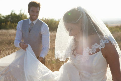 Neuvermählter Bräutigam hält Brautkleid, lizenzfreies Stockfoto