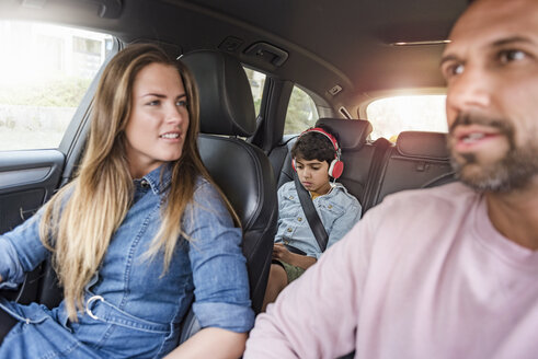 Familie auf einer Autoreise mit einem Jungen, der Kopfhörer trägt - DIGF04136