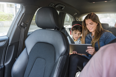 Familie auf einer Autoreise mit Mutter und Sohn, die sich ein Tablet teilen, lizenzfreies Stockfoto