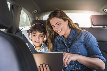 Familie auf einer Autoreise mit Mutter und Sohn, die sich ein Tablet teilen - DIGF04141