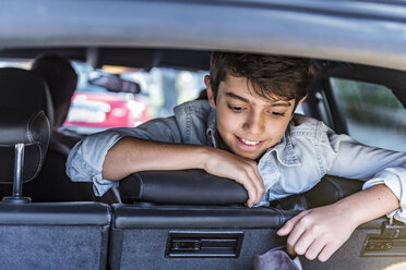 Lächelnder Junge im Auto schaut in den Kofferraum - DIGF04142